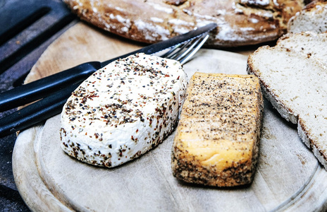  Zwei Käsearten auf einem Holzbrett mit Brotscheiben und Besteck.