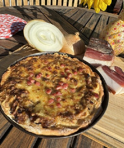 Stimmungsvoll dekorierter Gartentisch mit Wein, Käse und Lichterketten unter einem Baum.