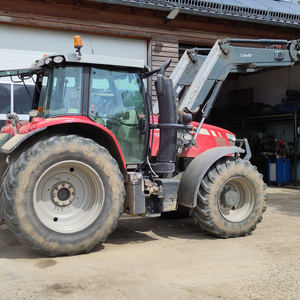 Ein roter Traktor steht vor einer Halle.