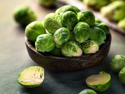 Eine Schale voller Rosenkohl, daneben ein halbierter Rosenkohl auf einem Tisch.