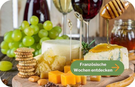 Stimmungsvoll dekorierter Gartentisch mit Wein, Käse und Lichterketten unter einem Baum.