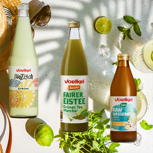 KI generiert: Drei Voelkel-Getränkeflaschen: BioZisch Zitrone, Fairer Eistee Grüner Tee Matcha, Raw Wasserkefir Ingwer Zitrone.