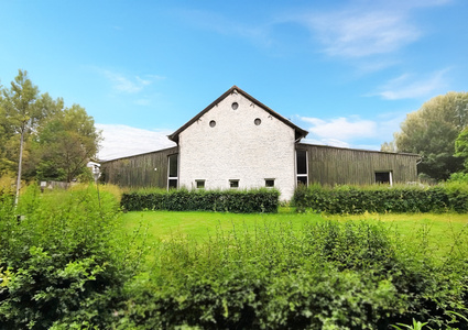  Ein weißes Gebäude mit grünem Garten und blauem Himmel im Hintergrund.