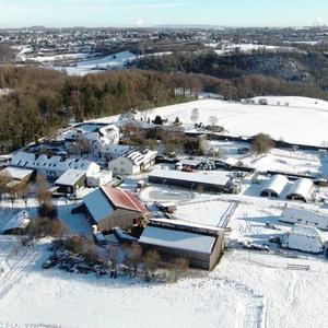 Schneebedeckte Landschaft mit einem Bauernhof und umliegenden Feldern.