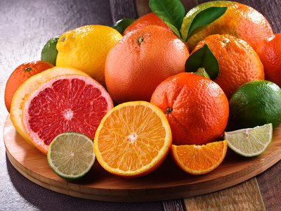  Verschiedene Zitrusfrüchte auf einem Holztablett, darunter Orangen, Grapefruits, Zitronen und Limetten.