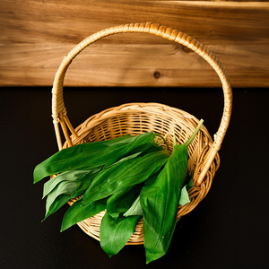 Korb mit frischem Bärlauch auf dunklem Hintergrund.