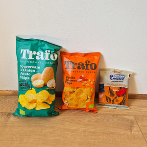Drei Tüten Bio-Snacks auf einem Boden. Text: "Trafo" und "Erdmann Hauser".