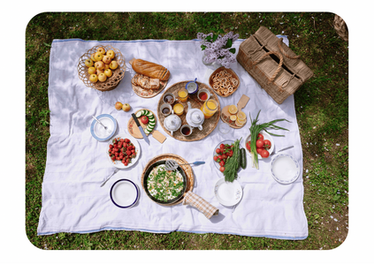 Stimmungsvoll dekorierter Gartentisch mit Wein, Käse und Lichterketten unter einem Baum.