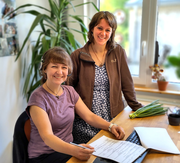 Zwei Frauen arbeiten zusammen am Computer in einem Büro.