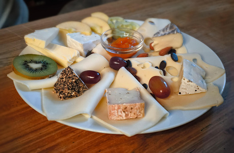 Eine Käseplatte mit verschiedenen Käsesorten, Früchten und Nüssen.