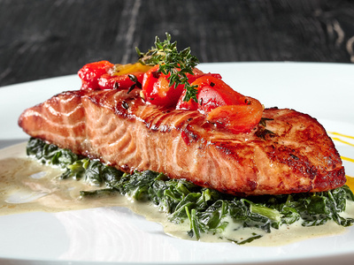 Ein Glas Bio-Erdbeerkonfitüre vor Erdbeeren, Aufschrift: "aus hofeigenen Früchten", "aus der Hofküche".