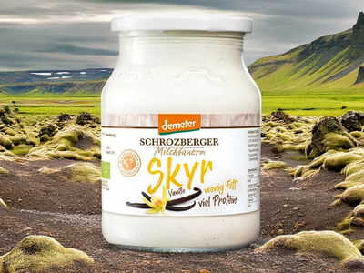 Ein Glas Skyr vor einer grünen, bergigen Landschaft. Text: Schrozberger Milchbauern Skyr Vanille.