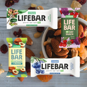  Verschiedene Sorten von Lifebar-Riegeln vor einer Schale mit Nüssen. Text: "gluten-free • vegan • organic".